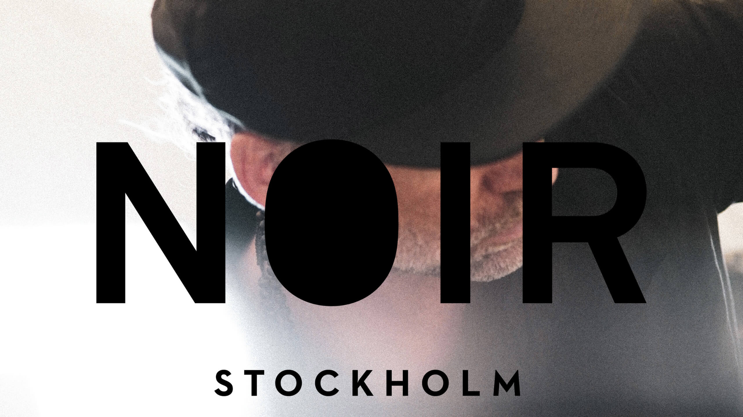 Noir Stockholm logotyp framför konstnärligt foto av en frisör i arbete – symbol för svensk professionell hårvård och design